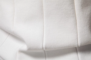 Dettaglio del tessuto bianco della polo in maglia con trama a coste verticali e trama