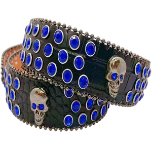 Macro detail of black croc-embossed leather belt with blue rhinestones and silver skulls