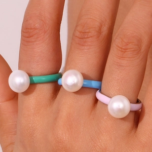 Macro shot of three colorful enamel rings with pearls in green, blue and pink hues