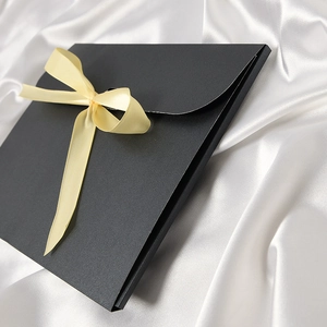 Elegant black envelope gift box with a light yellow silk ribbon bow on white silk