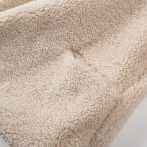 Close-up macro of soft beige sherpa fleece fabric showing curly fluffy texture