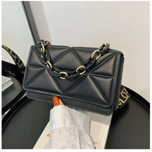 Detail of black quilted crossbody bag with chunky gold chain and jacquard wide strap