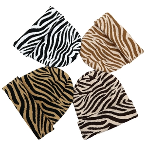 Detail shot of animal print knitted beanies in zebra and tiger patterns with four colors