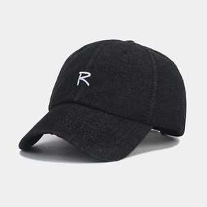 Macro detail of white embroidered R letter on black denim baseball cap with twill texture