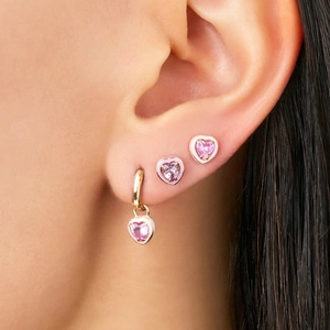 Detail of S925 silver heart cocktail hoop earring with pink gemstone and gold finish