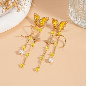 Close-up of golden butterfly tassel earrings with yellow crystals and white pearls