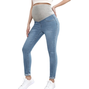 Detail of high waist maternity jeans with grey elastic belly support band in blue denim