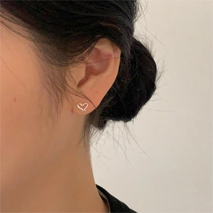 Close-up of minimalist silver heart stud earring worn on model for a trendy look