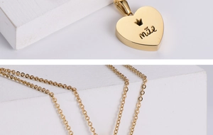 Macro detail of a gold heart pendant with Mae engraving and crown on a fine chain