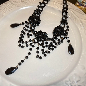 Macro detail of gothic black beaded flower necklace with dangling water drop crystals