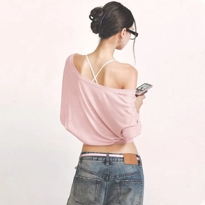 Detail of pink long-sleeve off-shoulder knit top with Y2K aesthetic and texture focus