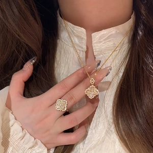 Close-up of a gold necklace and ring set with clover patterns and sparkling zircon stones