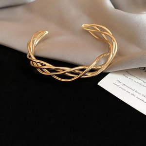 Detail of elegant gold layered twisted rope bangle featuring intricate woven metal texture