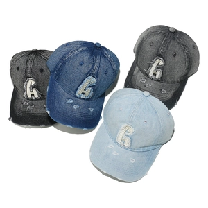 Detail of four vintage washed denim baseball caps with distressed holes and embroidered G letter