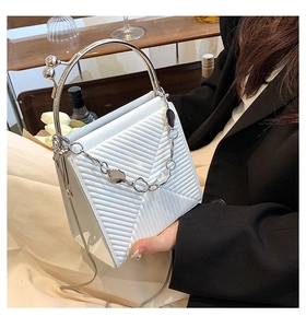 Detail of white quilted handbag with silver metal handle and chain in a cafe setting
