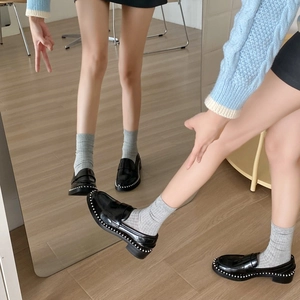 Gros plan de mocassins en cuir noir avec bordure en perles blanches sur miroir