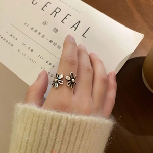 Macro shot of silver dual-flower open ring featuring vintage petal details and metal pistils