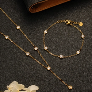 Macro detail of gold layered necklace and bracelet set featuring cubic zirconia accents