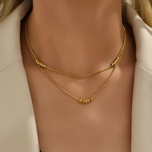 Minimalist double-layered 18K gold snake chain necklace with solid beads on a model