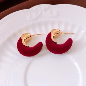 Détail de boucles d'oreilles C en velours rouge avec placage or 18K sur plateau céramique