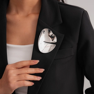 Close-up of a silver irregular geometric brooch on a black blazer with high mirror finish
