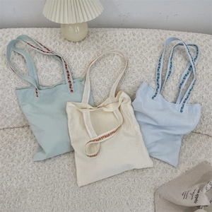 Gros plan détaillé de trois sacs fourre-tout en toile avec bandoulières brodées de fleurs