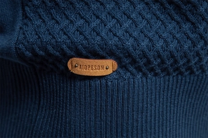 Detail of cable knit pattern and leather logo patch on navy blue cotton sweater