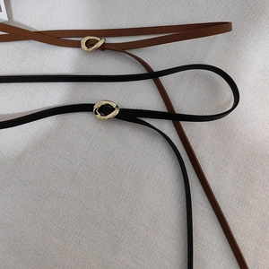 Detail of minimalist leather belts with gold organic irregular metal buckles in black and brown
