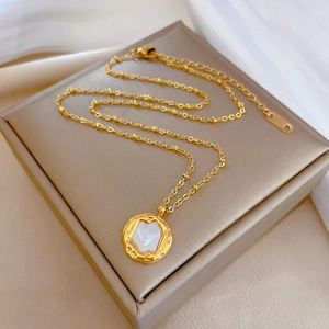 Macro shot of gold plated titanium necklace with irregular shell pendant on satin