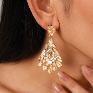 Detailed view of luxury champagne crystal drop earrings worn by a model in warm lighting