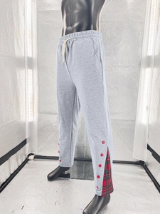 Détail du jogging gris avec fente boutonnée rouge et empiècement à carreaux rouge et vert