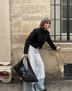 Stile street di una giacca corta nera doppiopetto abbinata a una gonna di pizzo bianca