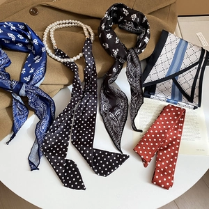 Polka dot silk scarf necklace with luxury pearls on an autumn coat background