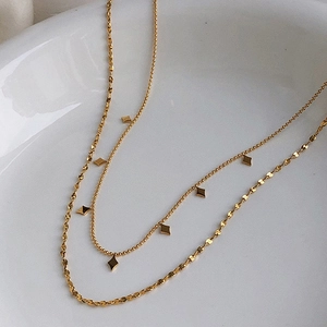 Detail of layered gold necklaces with rope chain and star pendants on white ceramic tray