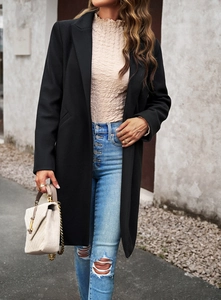 Chic black mid-length wool coat styled with blue ripped jeans and a beige handbag outdoors