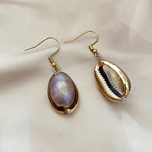 Elegant bohemian shell drop earrings with gold plating on premium beige silk background