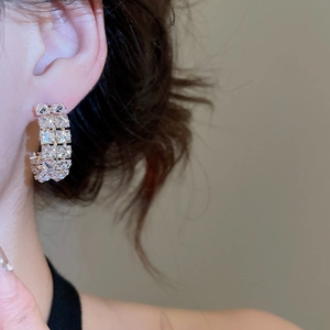 Close-up of double-row cubic zirconia C-shaped hoop earrings worn by a model