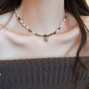 Close-up of beaded necklace with tiger eye stones and a gold-edged turquoise pendant