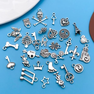 Macro shot of assorted silver alloy charms including skulls and hearts on blue surface