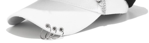 Detailed macro view of white cotton baseball cap featuring three silver metal rings on the brim