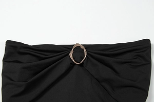 Detail of elegant black knit dress featuring a gold metal ring buckle and gathered pleats