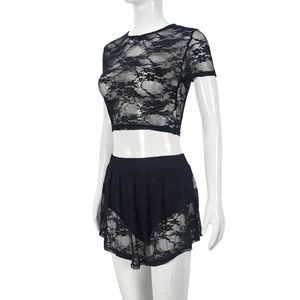 Detail van bloemige zwarte kanttextuur op een crop top en bijpassende minirok