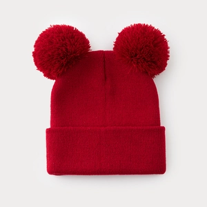 Dettaglio del berretto in maglia rossa con doppi pompon soffici e trama intrecciata