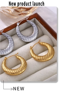 Detailed view of U-shaped gold and silver earrings with quilted texture in a gray box