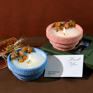 Handmade scented candles in textured rock clay jars with dried roses and gift cards