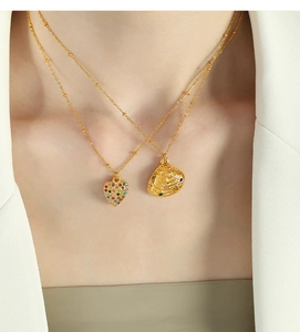 Close-up of layered gold necklaces featuring a colorful heart pendant and a textured shell charm