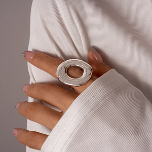 Detail shot of a hollow circular silver metal ring worn on a finger for a minimalist look