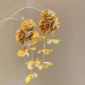 Close-up of yellow chiffon fabric flower earrings with elegant gold metal details
