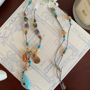 Colorful turquoise oval pendant necklace with bohemian style beads on white card