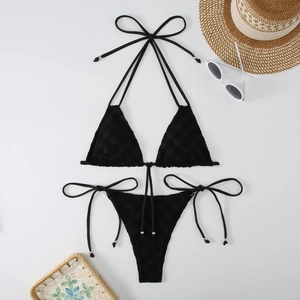 Flat lay of black bikini with checkered texture and stylish beach vacation accessories